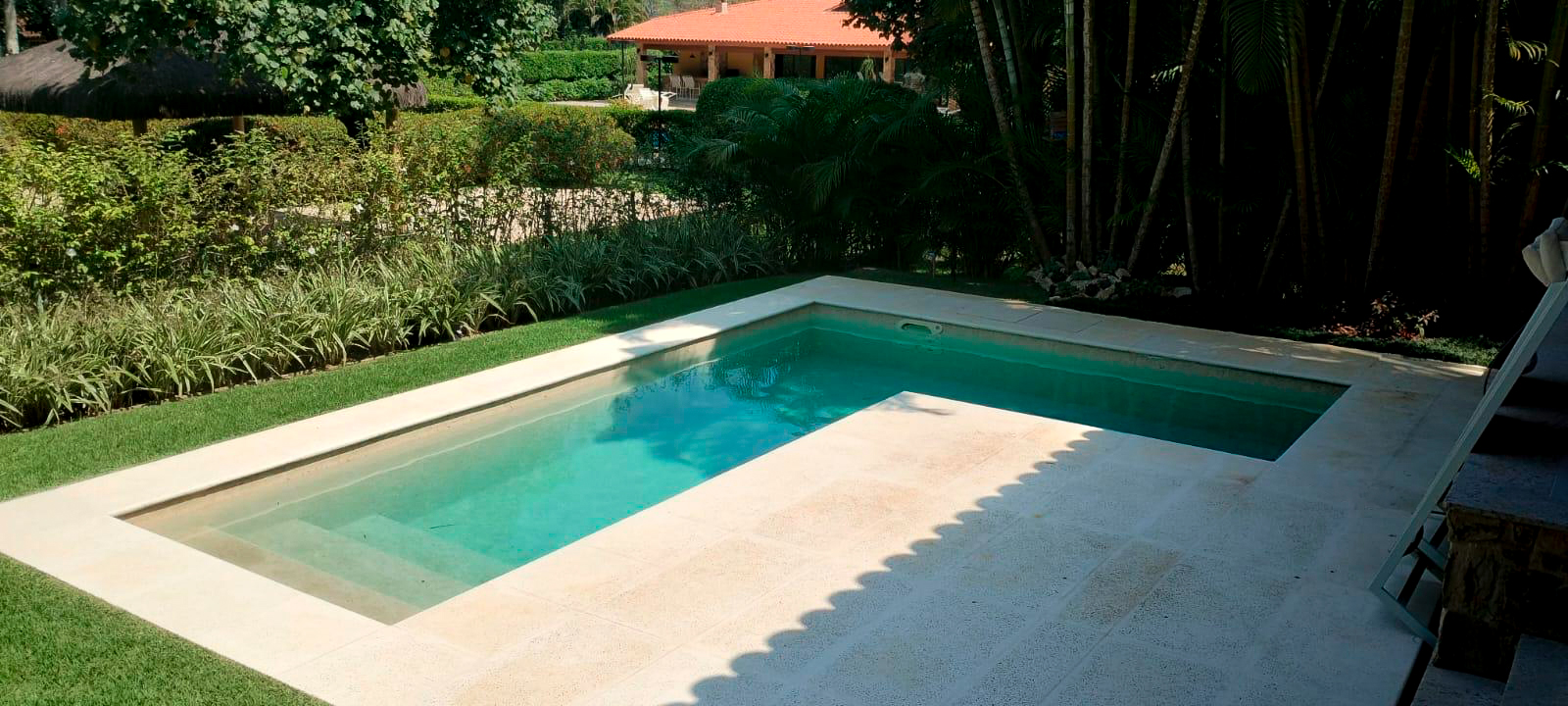 Uma piscina com o formato de L em um quintal de uma casa