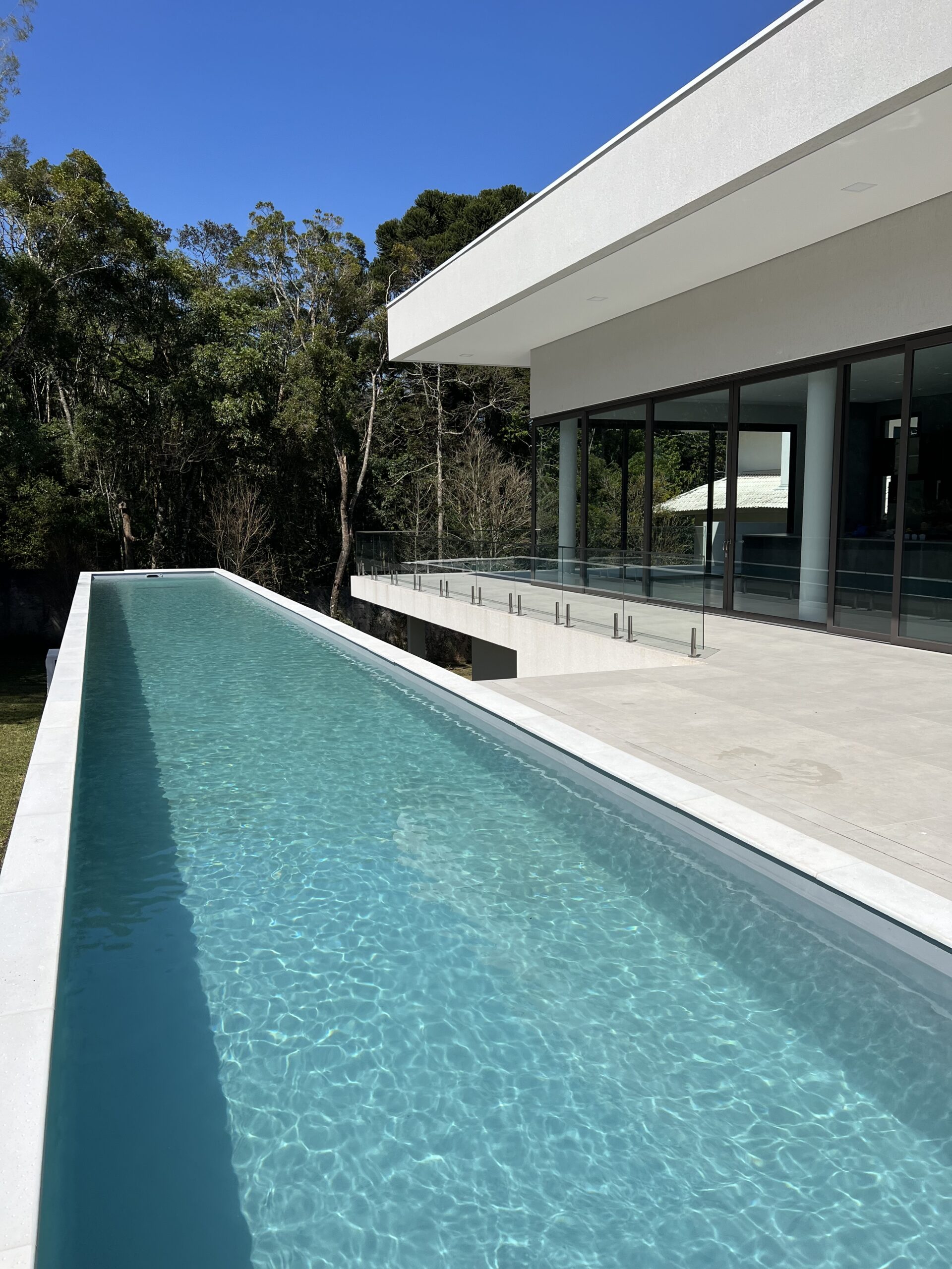 Uma piscina com raia na área externa de uma casa grande e moderna